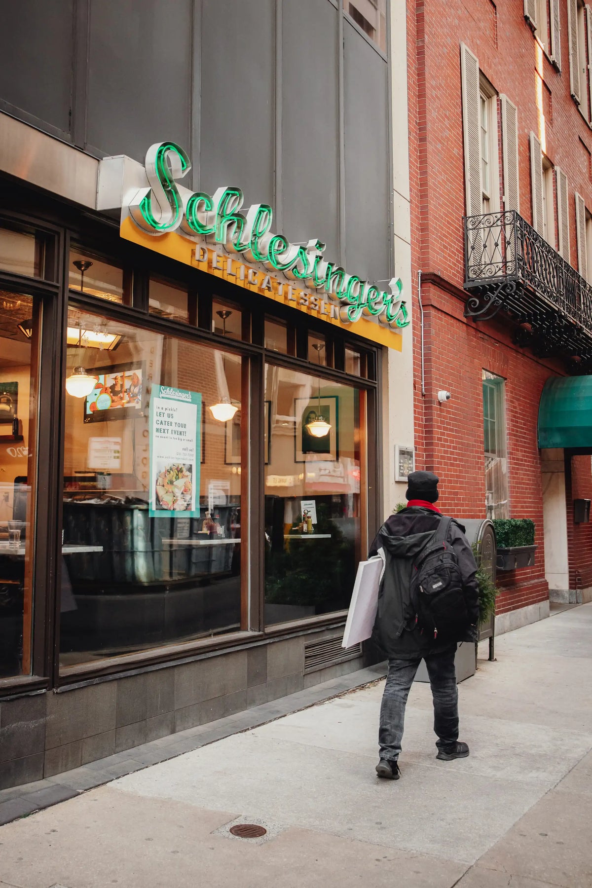 Person walking past a Schlessingers restaurant on a city street
