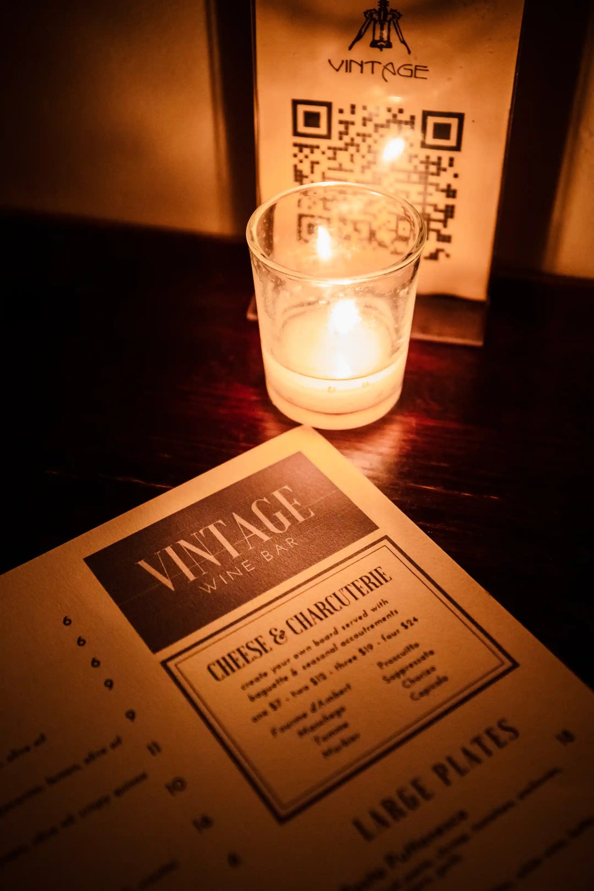 Vintage wine bar menu with a lit candle on a wooden surface