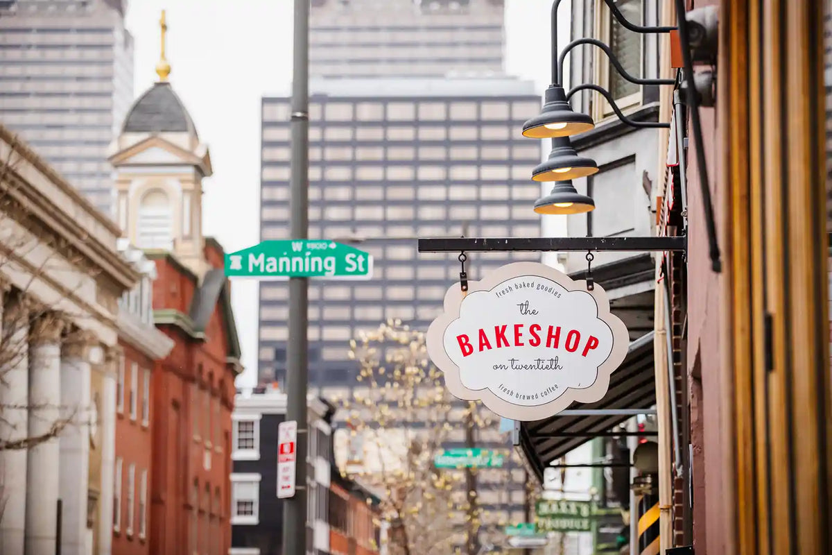 The BakeShop sign hanging outside a building with cityscape in the background
