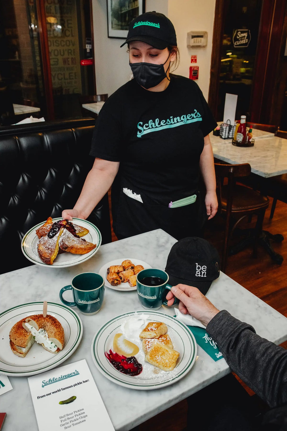 Person serving food at a restaurant with a 'Schlesinger's' shirt on.