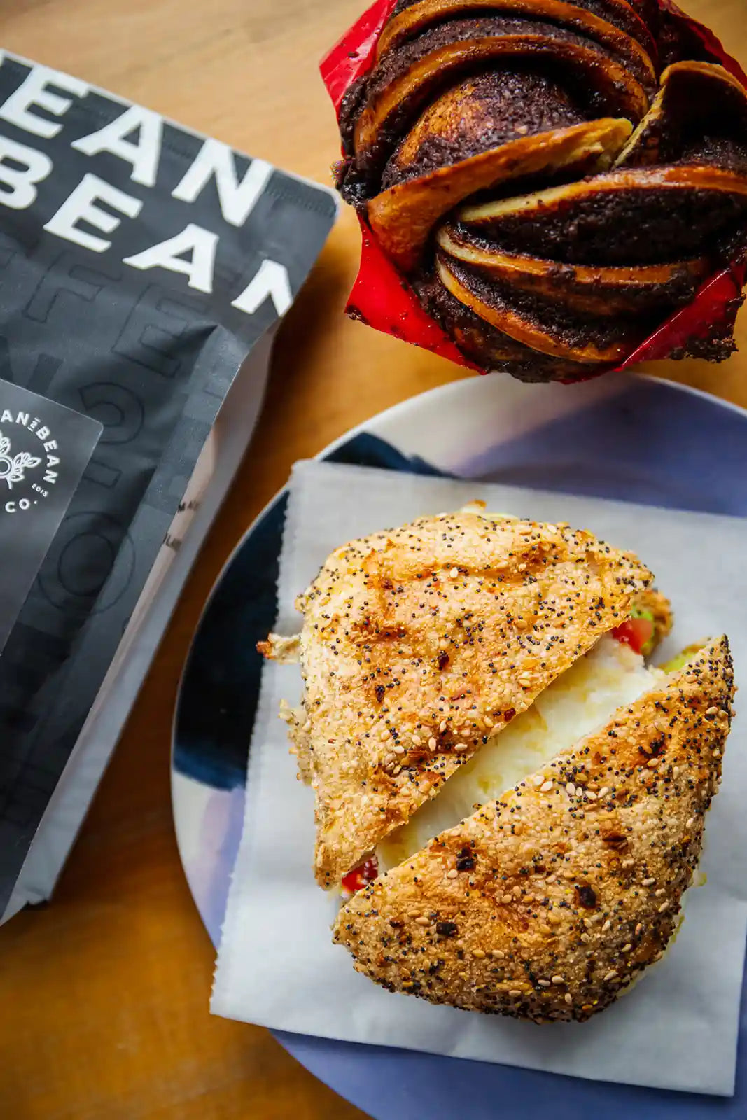 Cinnamon muffin and breakfast panini sandwichon a plate next to a package labeled 'Bean2Bean'.