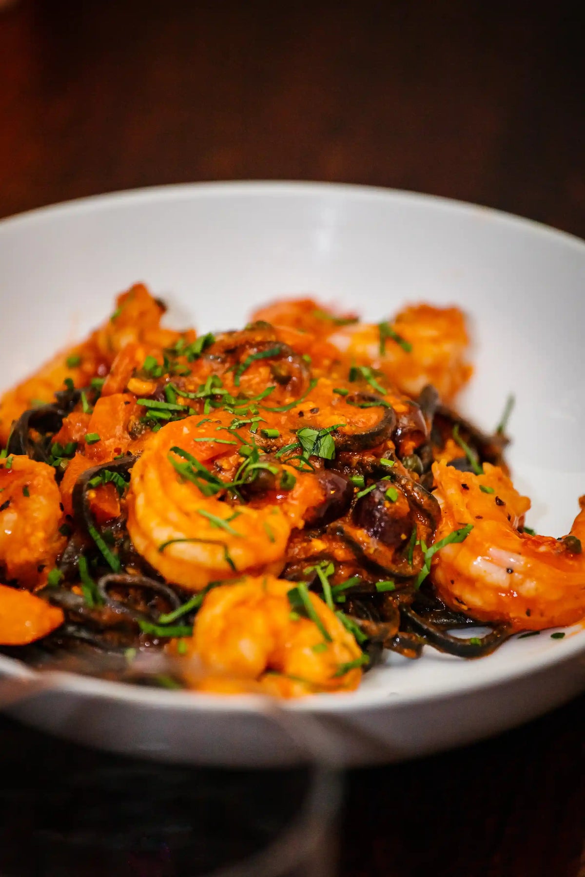 Shrimp dish with sauce and herbs on a white plate