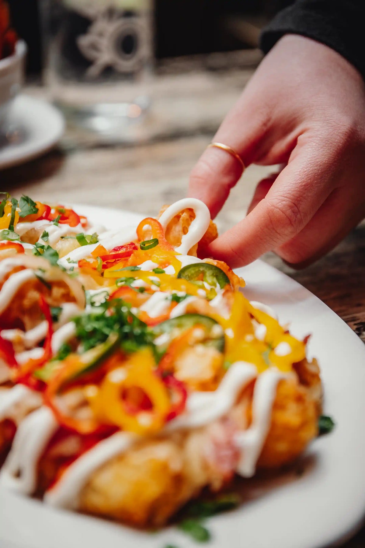 Hand reaching for a plate of nachos with a blurred background