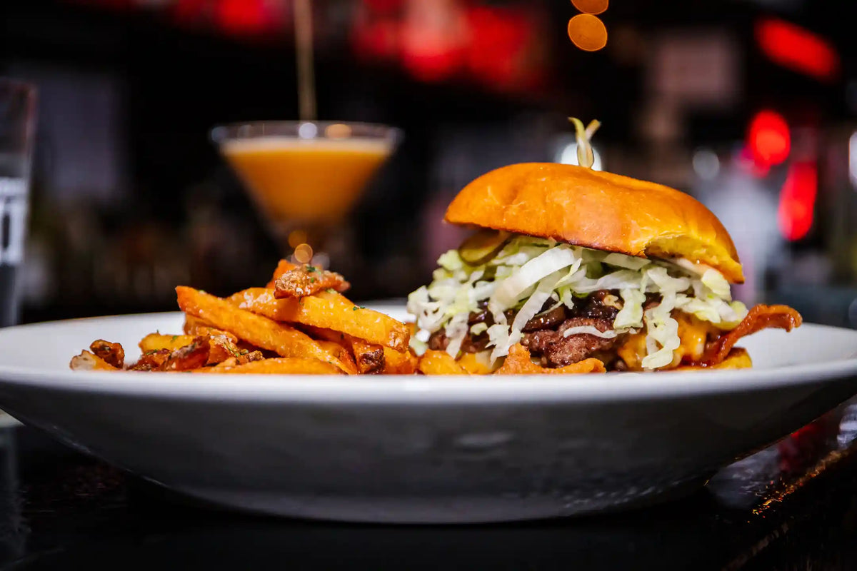 Burger with fries on a white plate in a bar setting