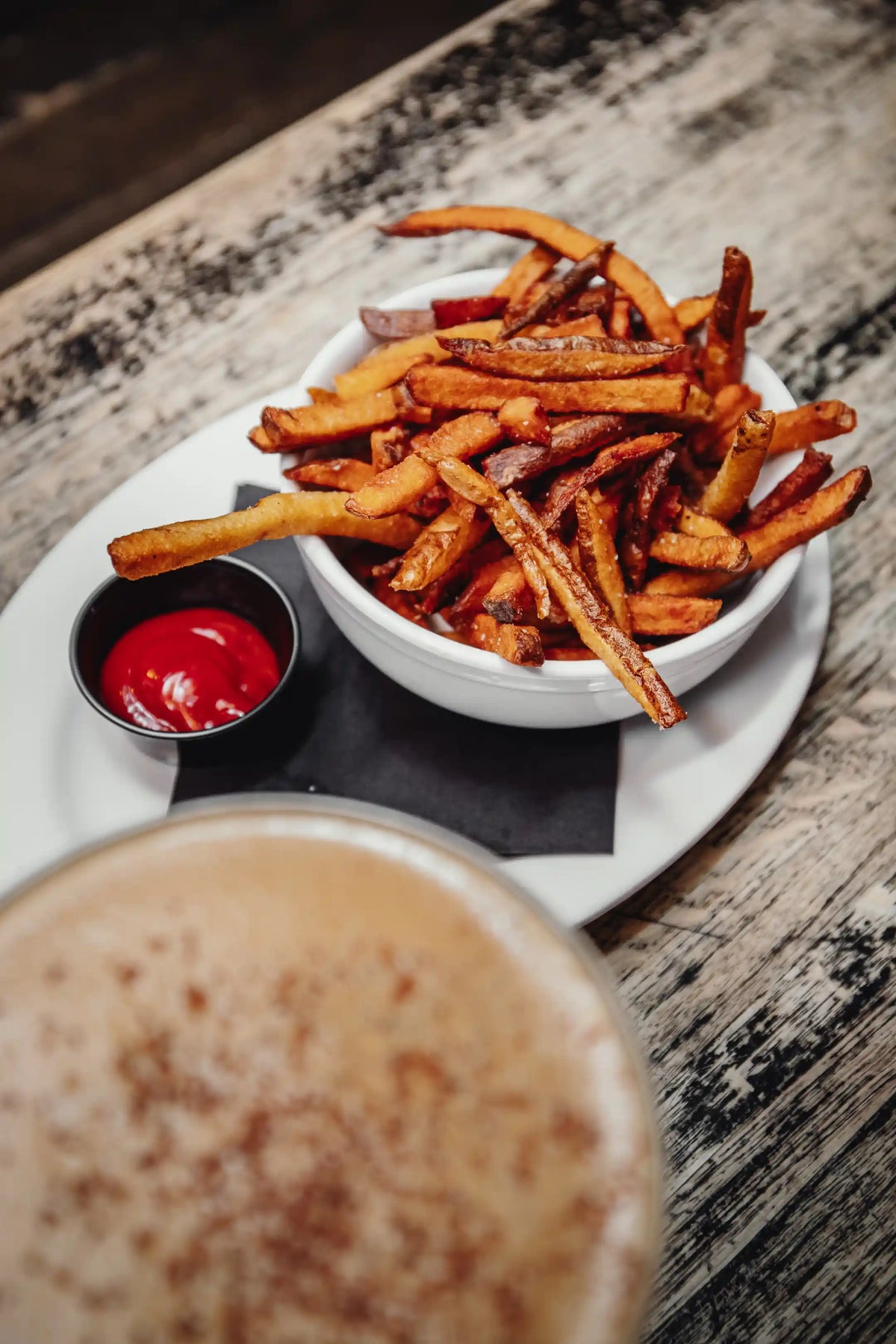 Bowl of fries with a side of ketchup on a wooden table