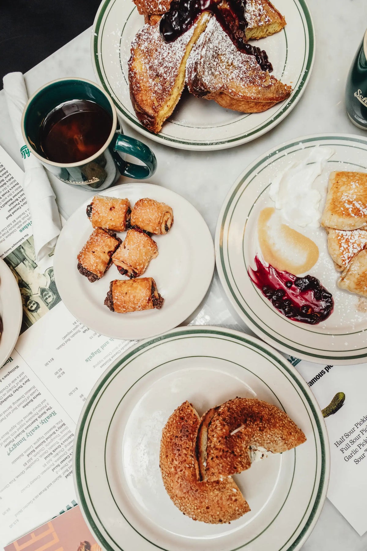 Assorted pastries on plates with a cup of coffee on a newspaper.