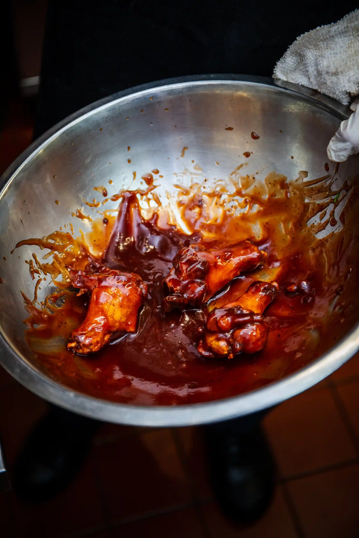 Coating hot wings in sauce in a metal bowl