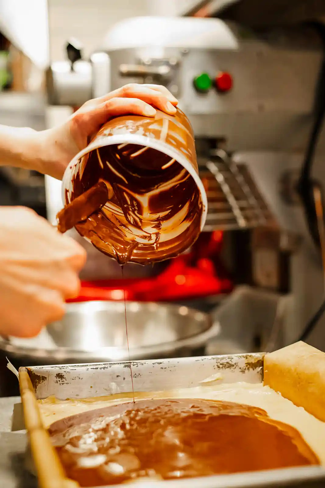 Person spreading chocolate frosting onto a cake with a spatula