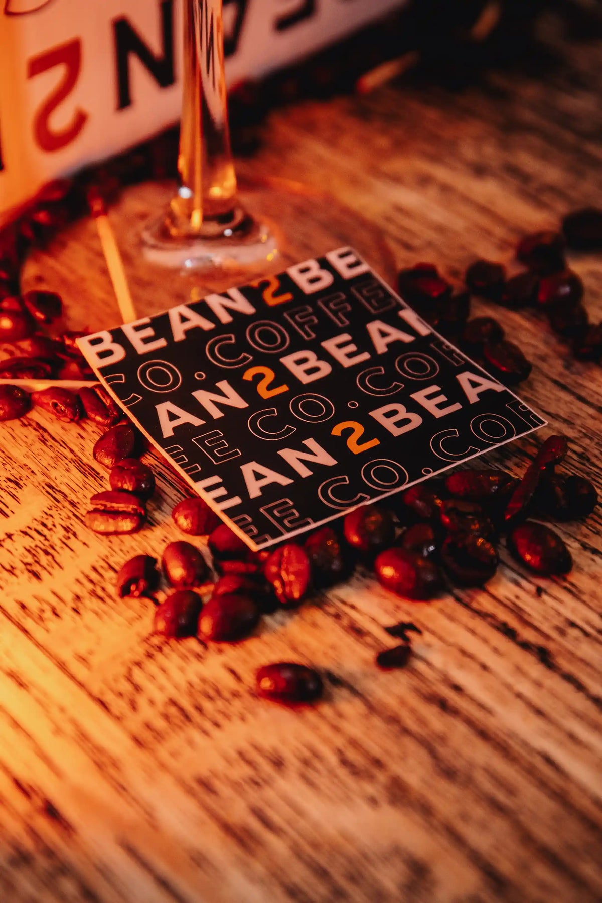 Card with 'BEAN2BEAN COFFEE CO' branding surrounded by coffee beans on a wooden surface