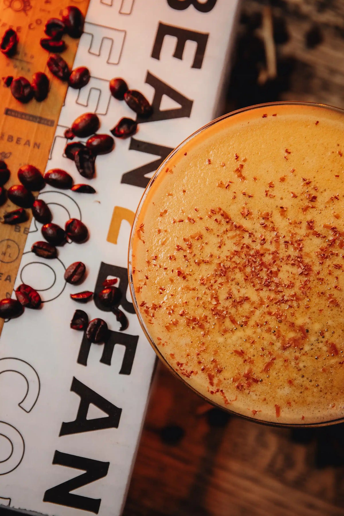Close-up of a Espresso martini glass with placed on a surface with 'Bean2Bean' branding.