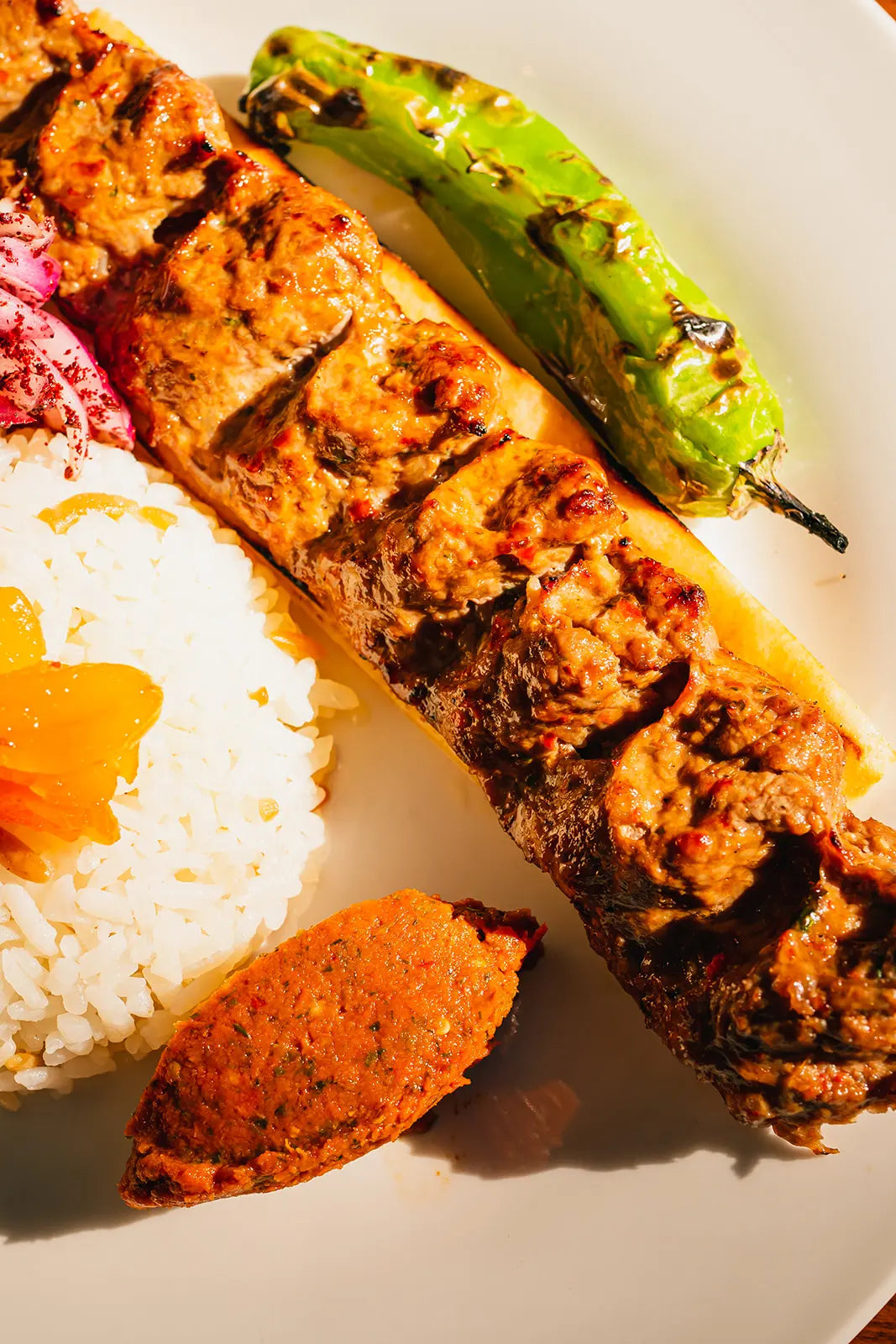 Grilled kebab with rice and shishito pepper with rice on a white plate