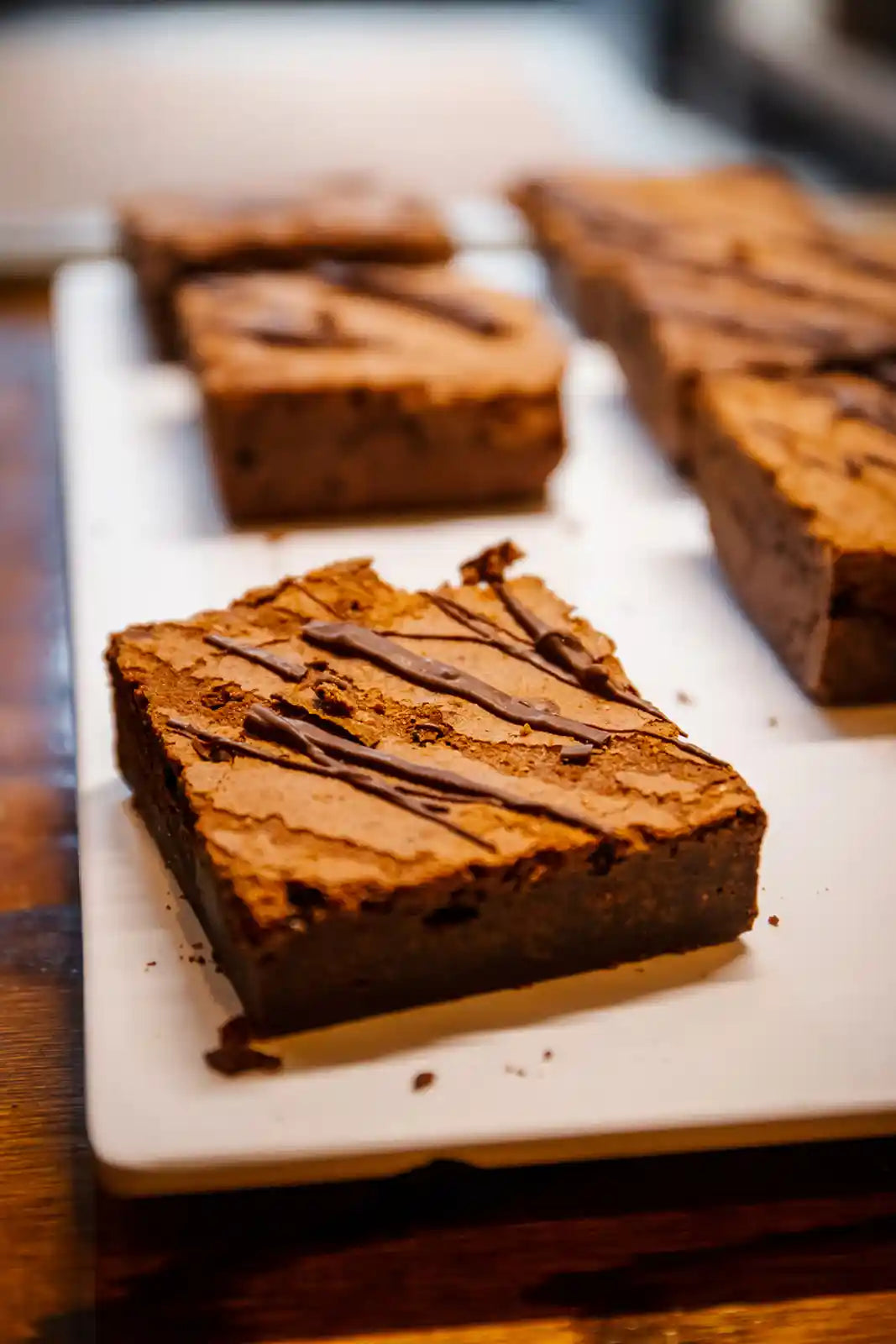 Chocolate brownies with a drizzle on a white marble slab.