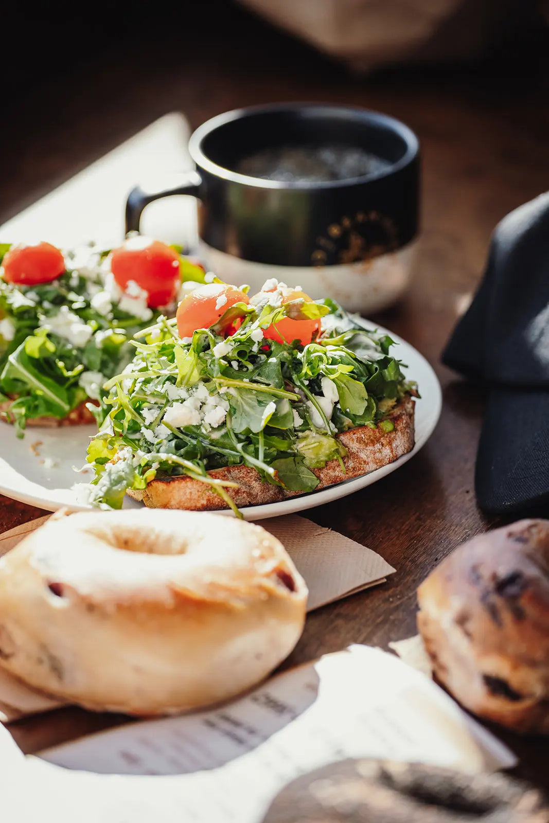 Plate of salad with a cup of Bean2Bean coffee and bread on a wooden table