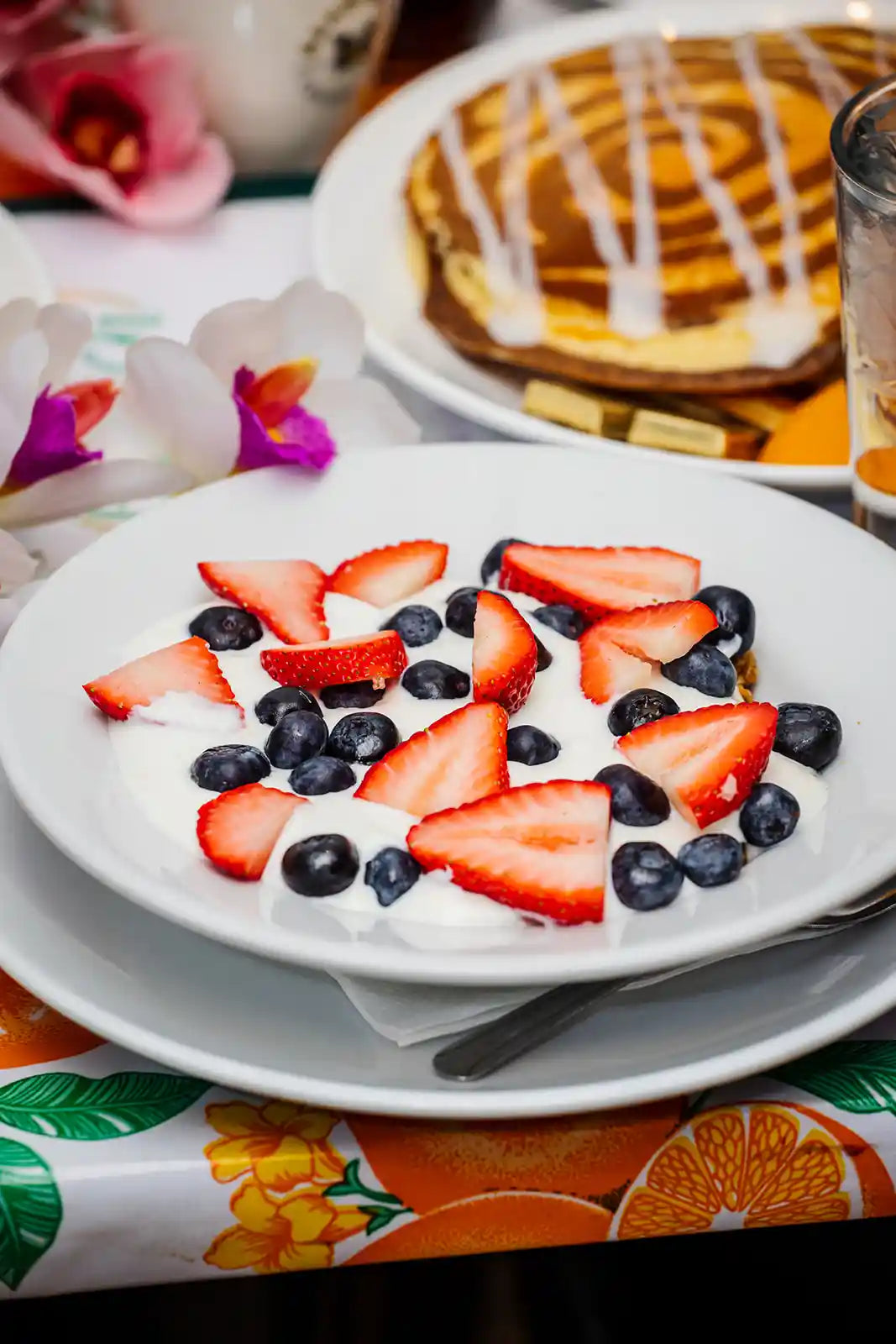 Fruit salad with strawberries and blueberries on a plate with a colorful tablecloth.