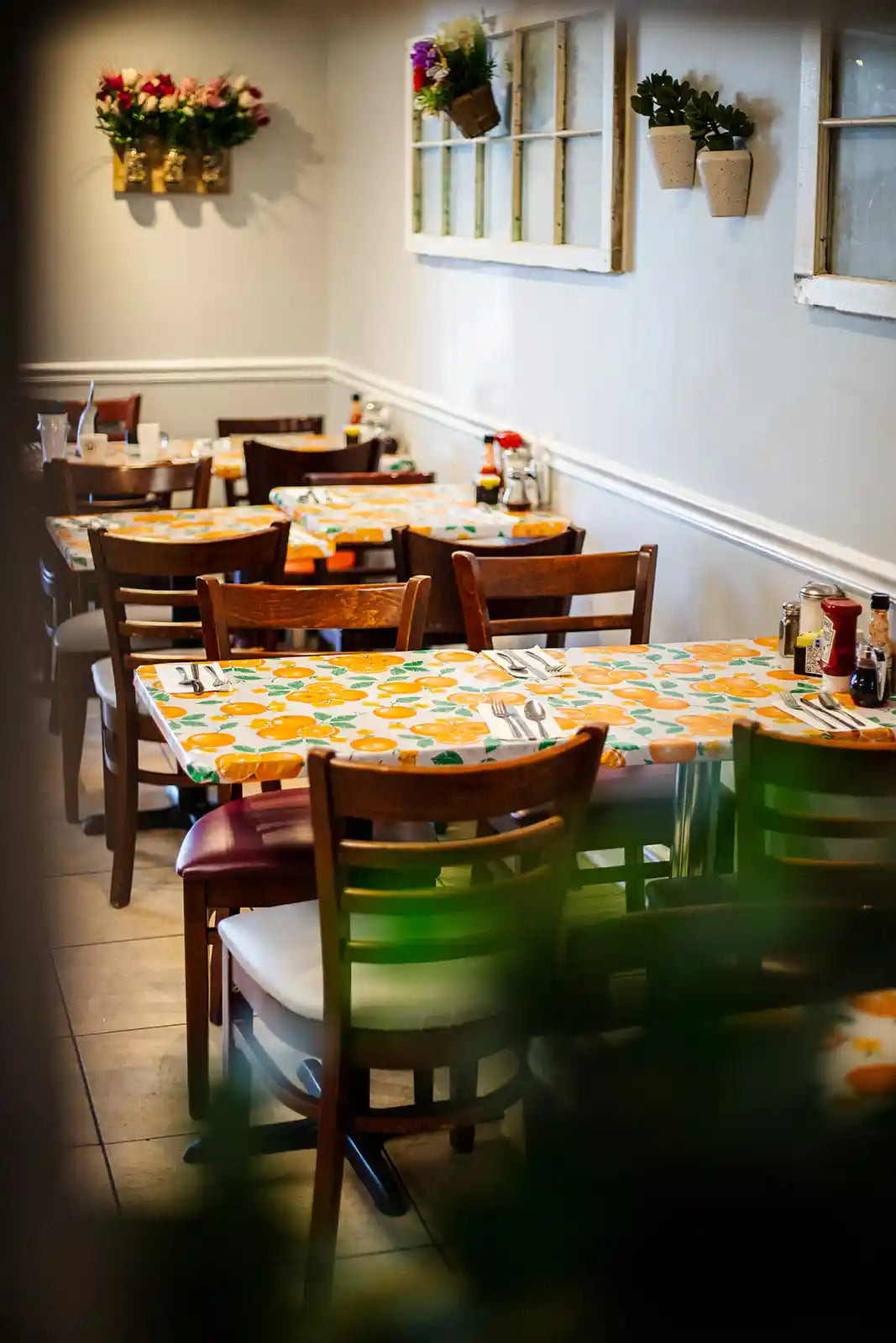 Dining area with tables, chairs, and floral decorations on a wall.