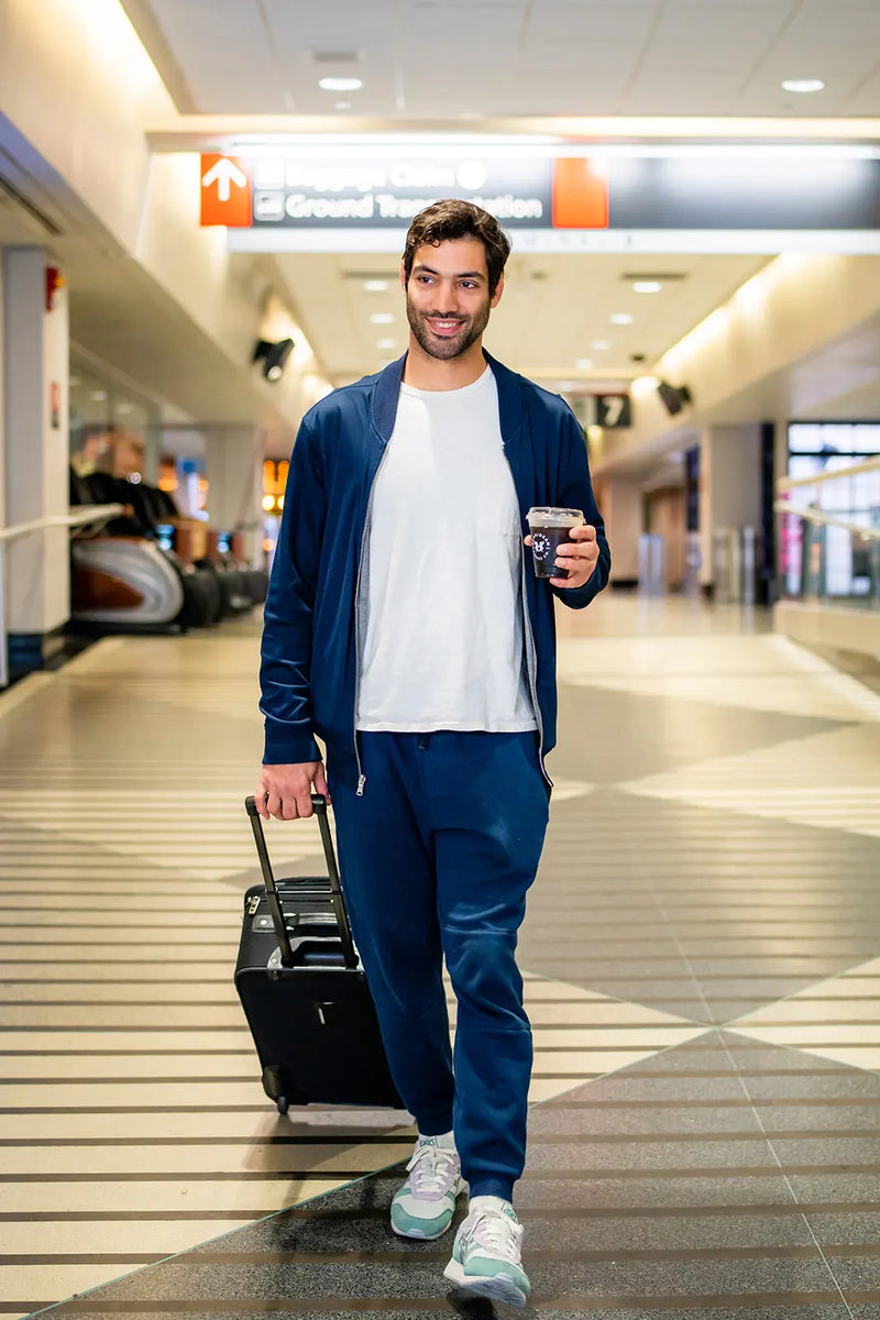 Man walking through an airport with a suitcase and a Bean2Bean Cold Brew