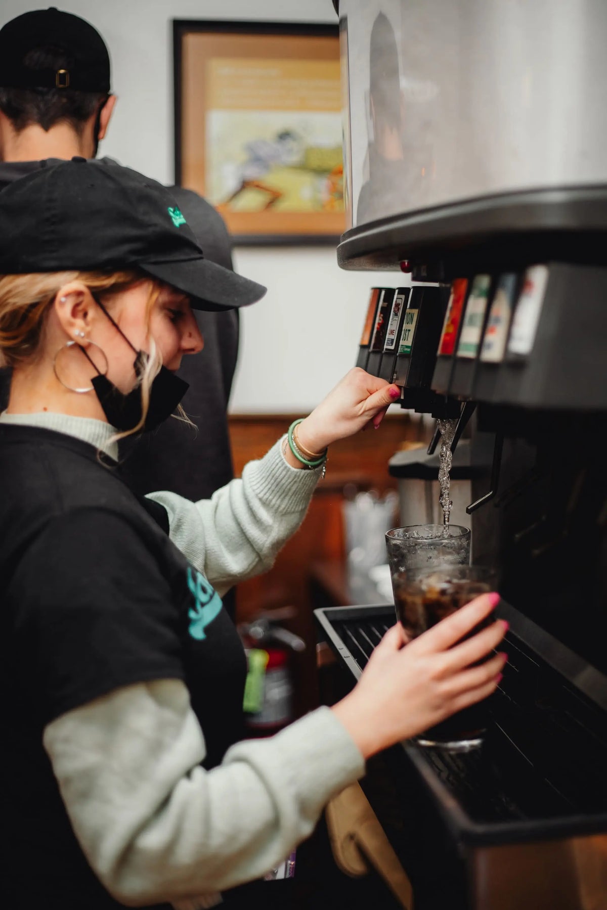 Person using a soft-drink machine in a kitchen setting