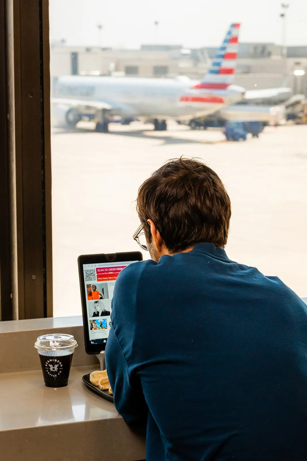 Person using a laptop at PHL airport with airplanes visible outside