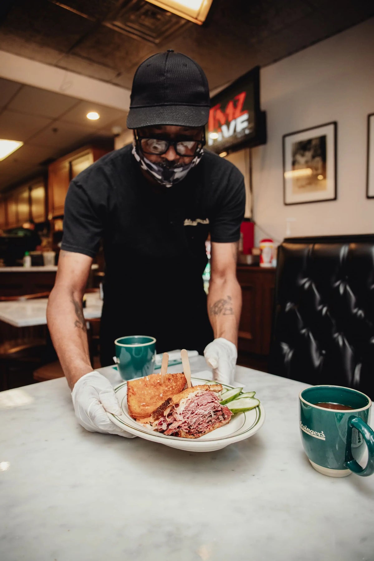 Person in a restaurant setting holding a plate with food and a mug.