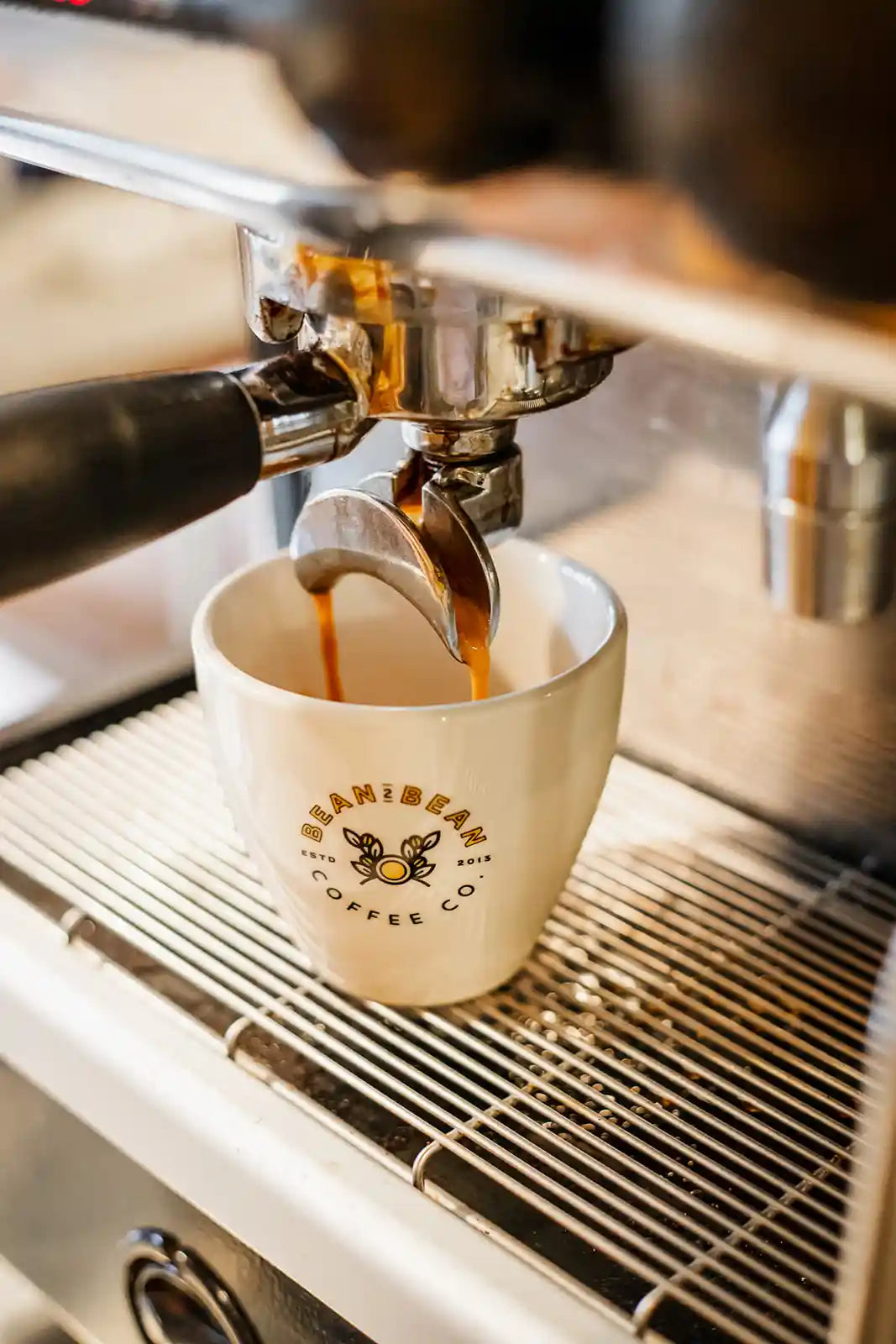 Espresso being poured into a white cup with 'Bean2Bean Coffee Co.' branding.