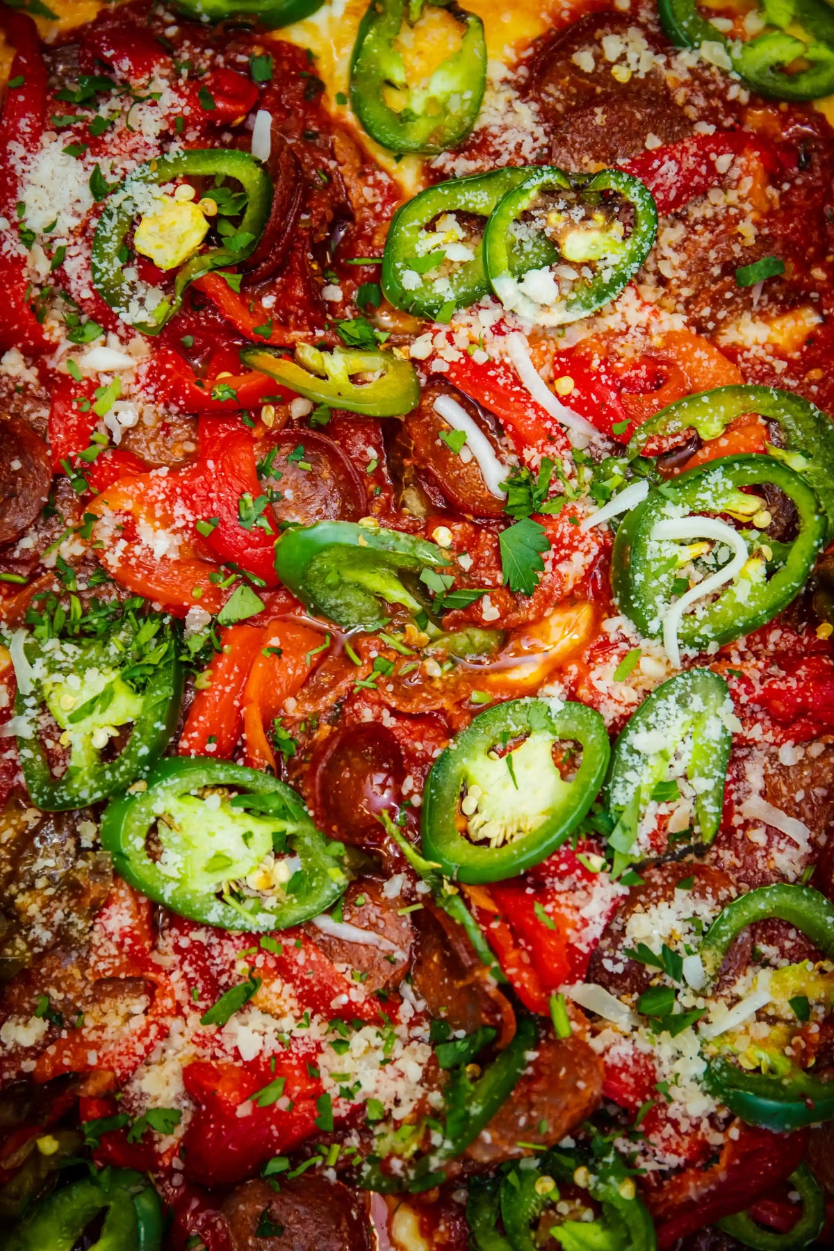 Close-up of a pizza with jalapeños, cheese, and other toppings
