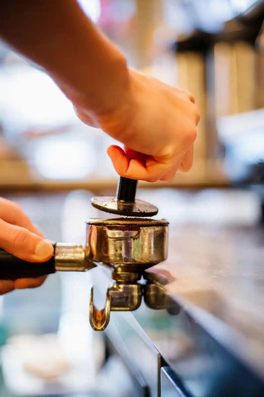 Hand using a coffee tamp to press grounds into a portafilter.