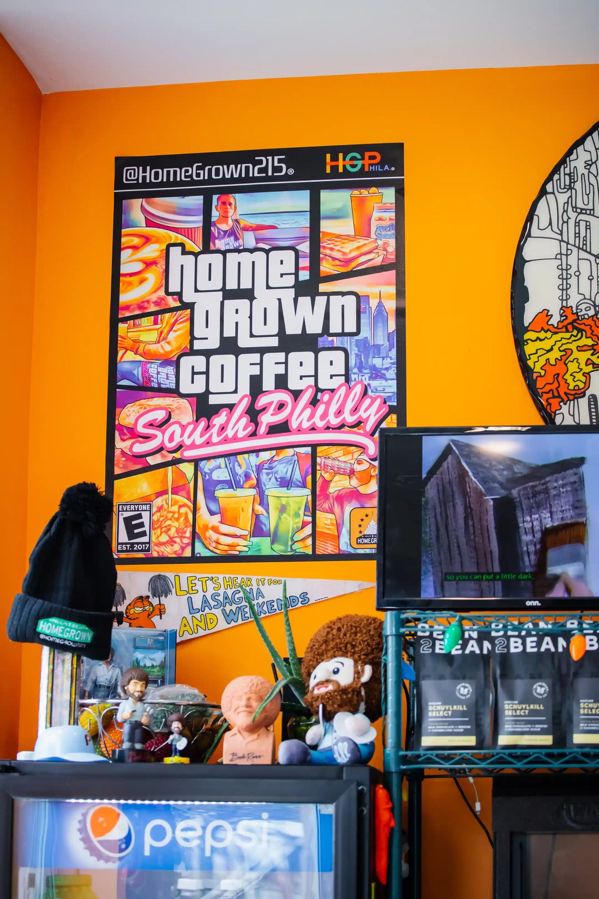 Display of 'Home Grown Coffee South Philly' with various coffee products and a Pepsi sign on an orange wall.
