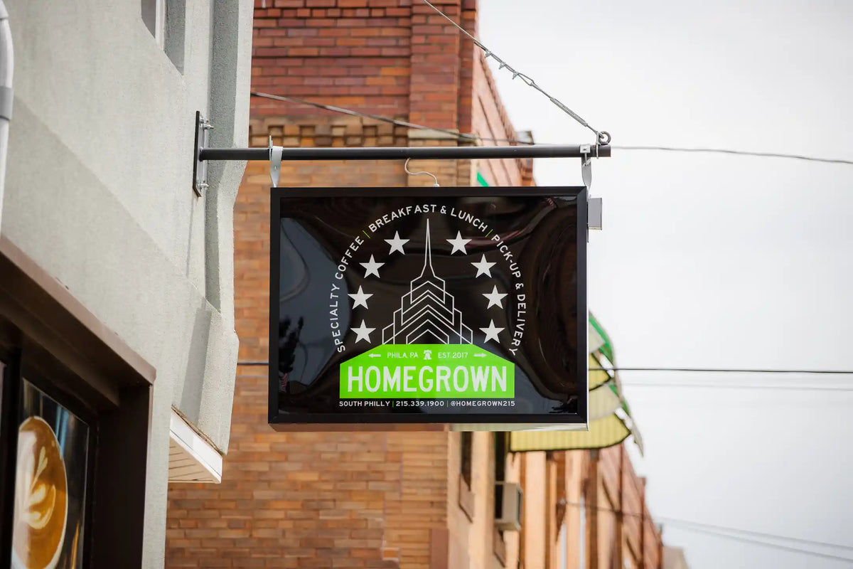 Black and green sign hanging outside a building with 'Homegrown' branding.