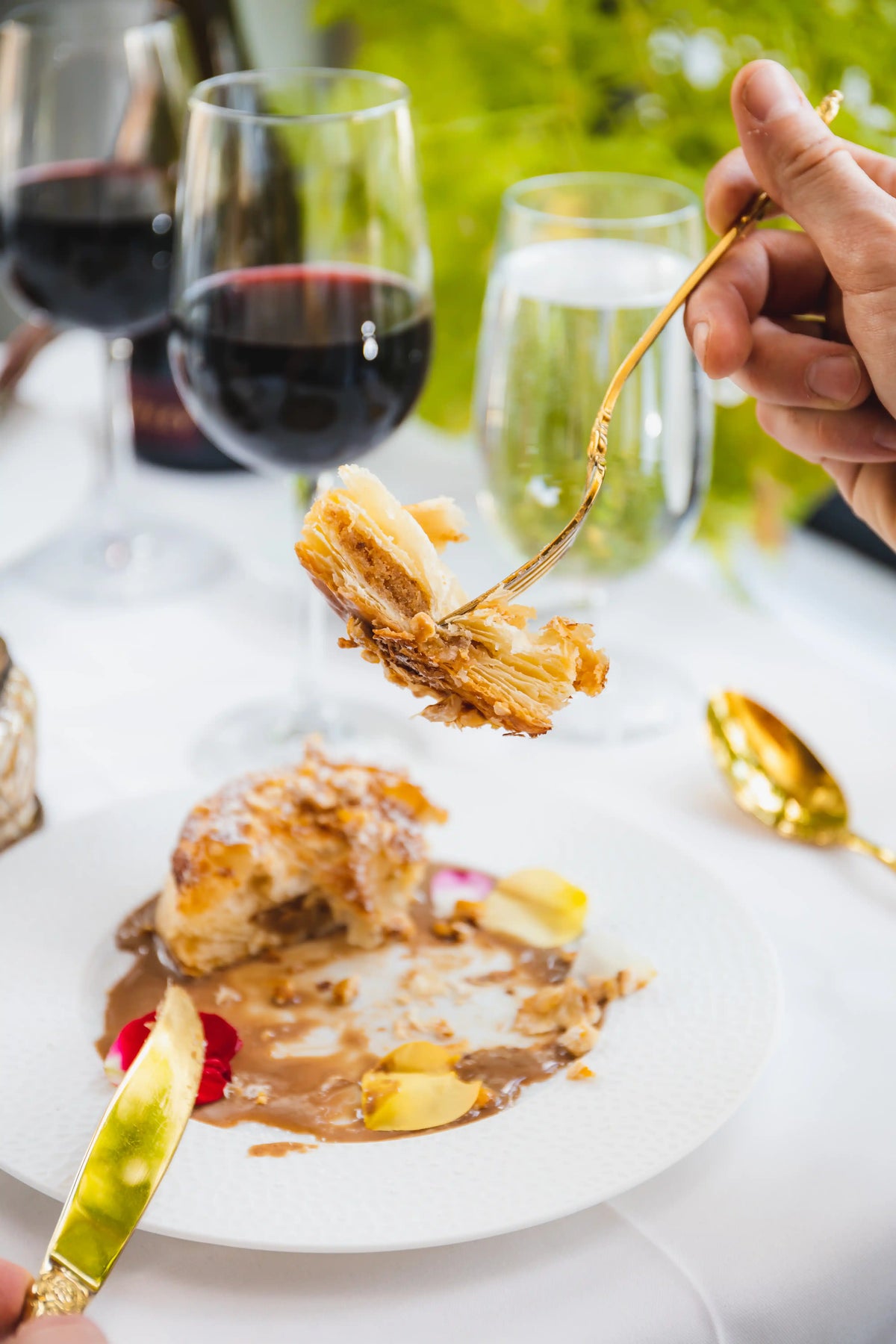 Dessert being served with a fork, wine glasses in the background