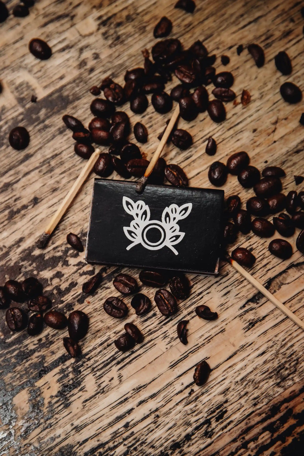 Coffee beans scattered on a wooden surface with a small black sign featuring a white Bean2Bean Coffee Co. logo
