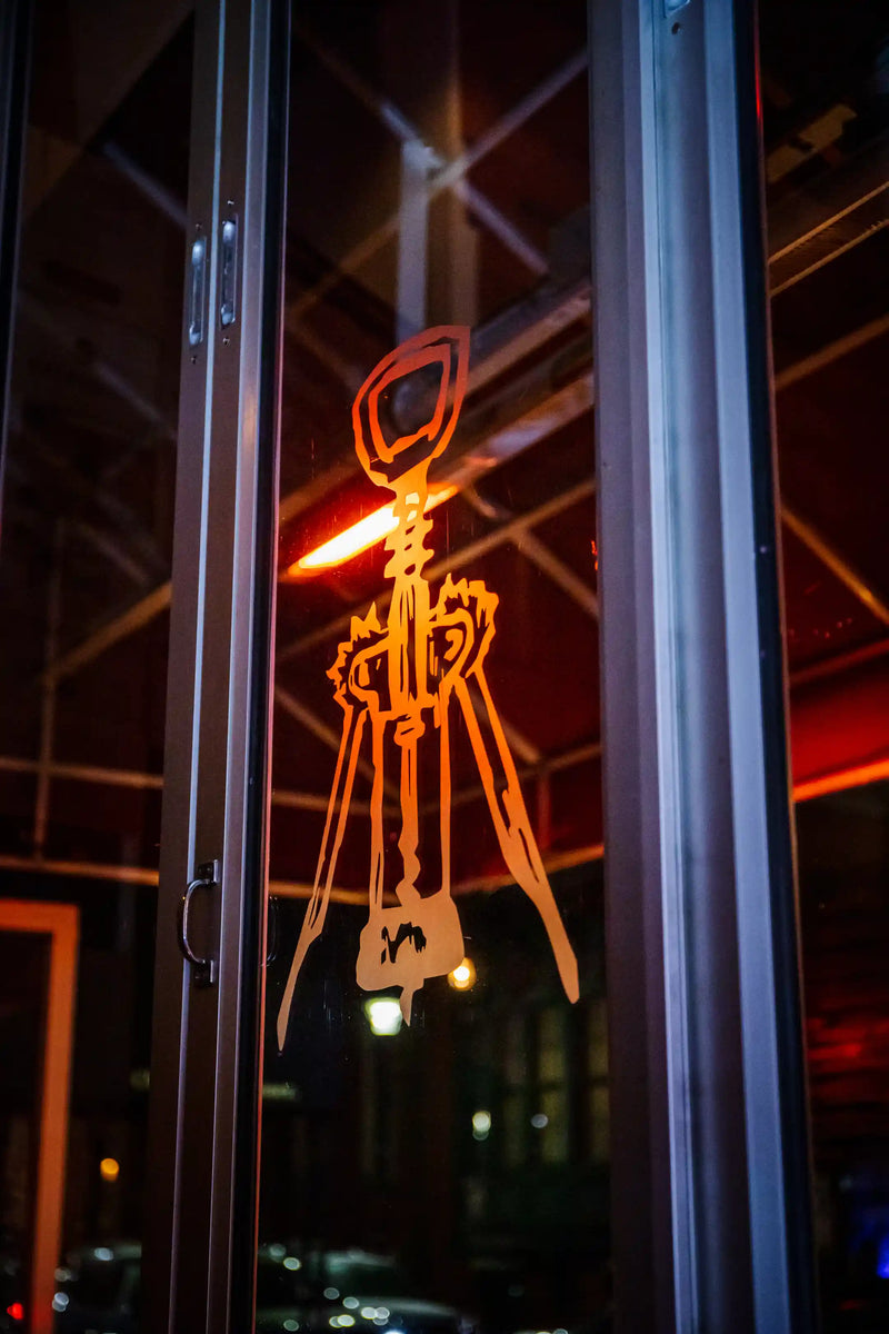 Vintage Wine Bar logo on a glass door with reflections of lights at night