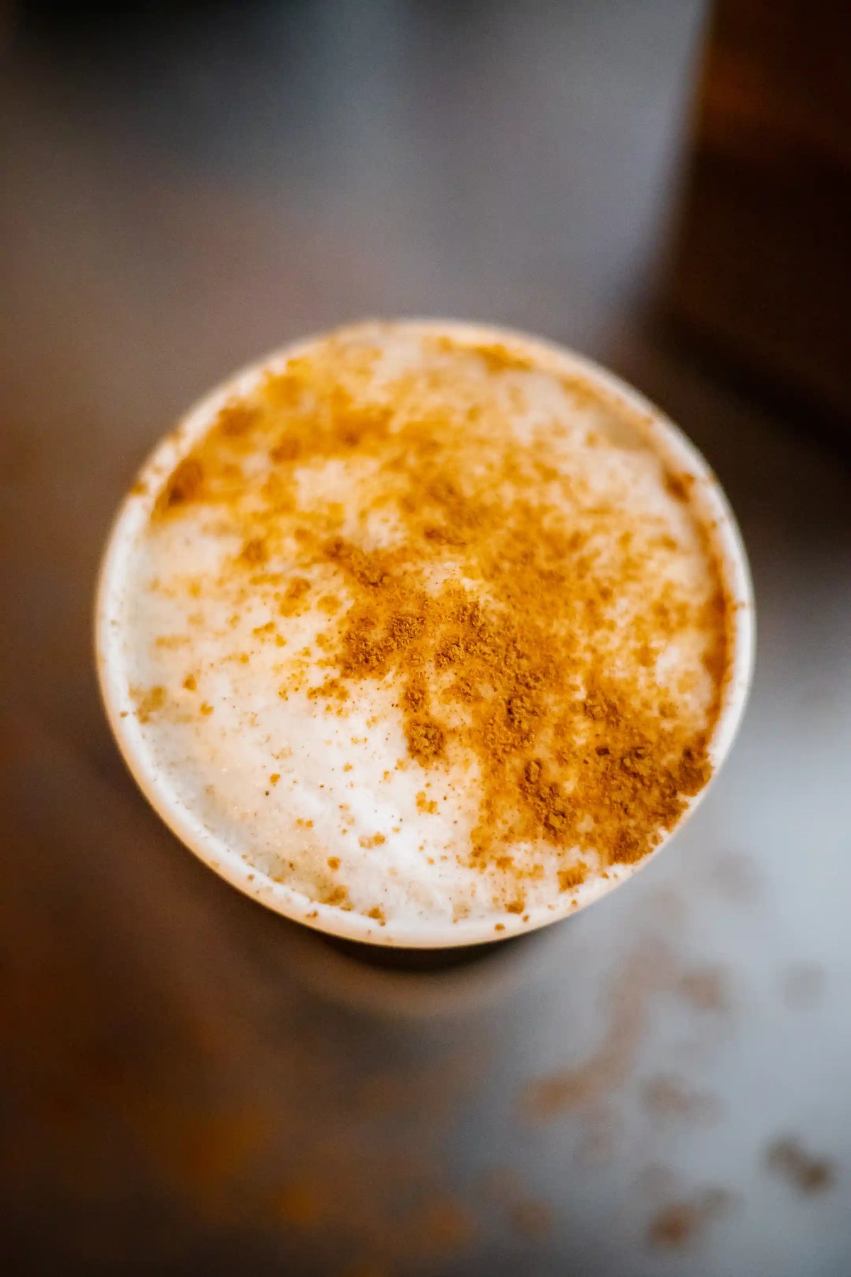 Close-up of a cup of coffee with a creamy top on a blurred background