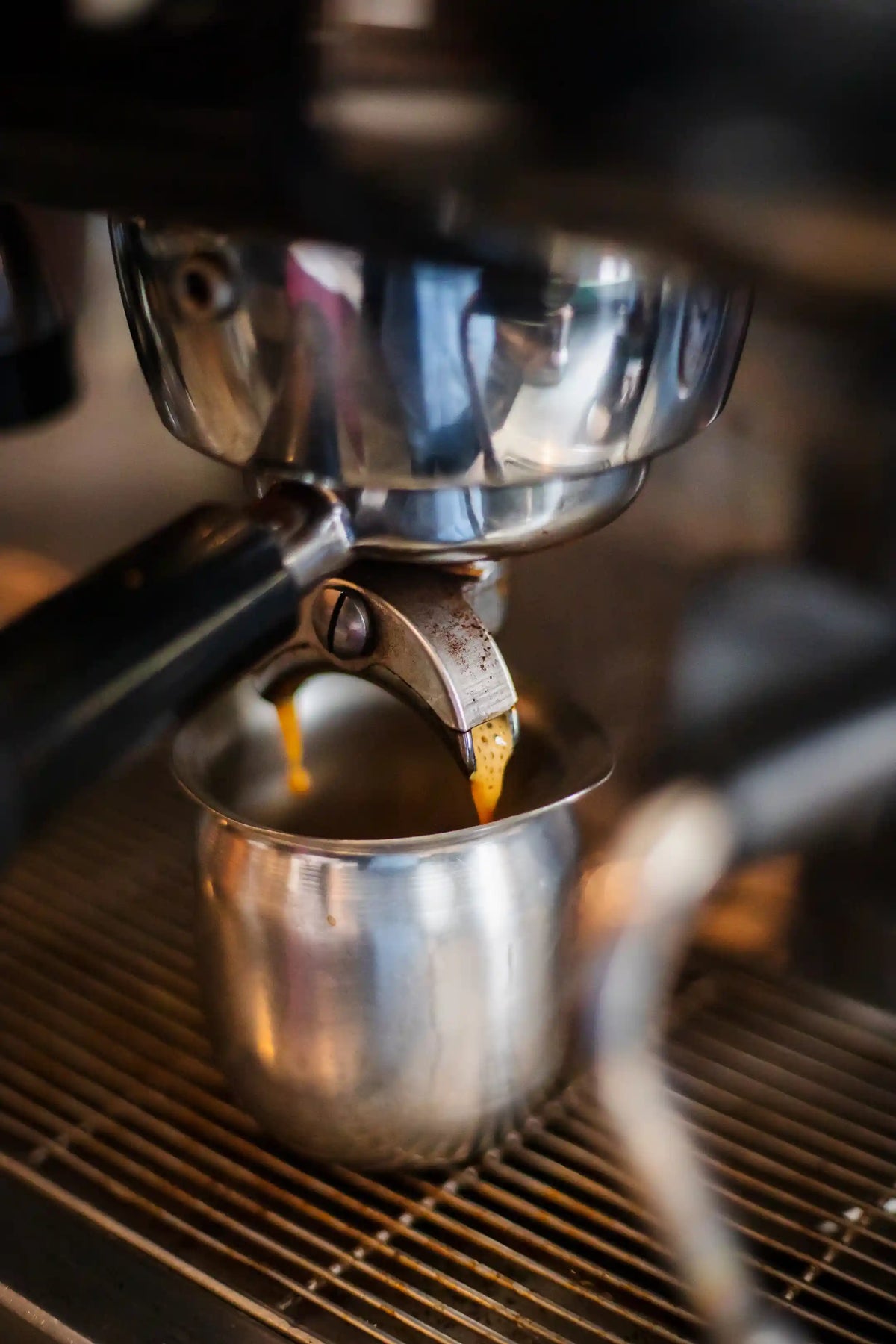 Espresso being extracted into a metal portafilter basket.