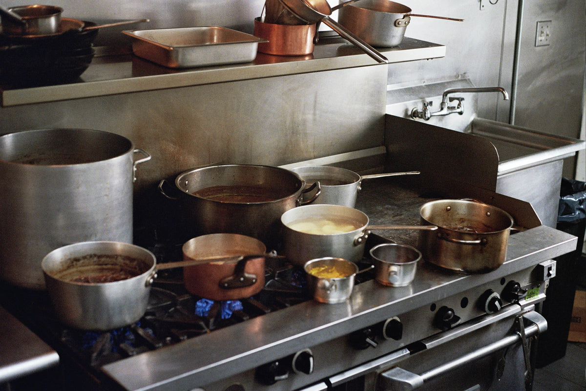 Pots and pans on a professional range stovetop in a kitchen