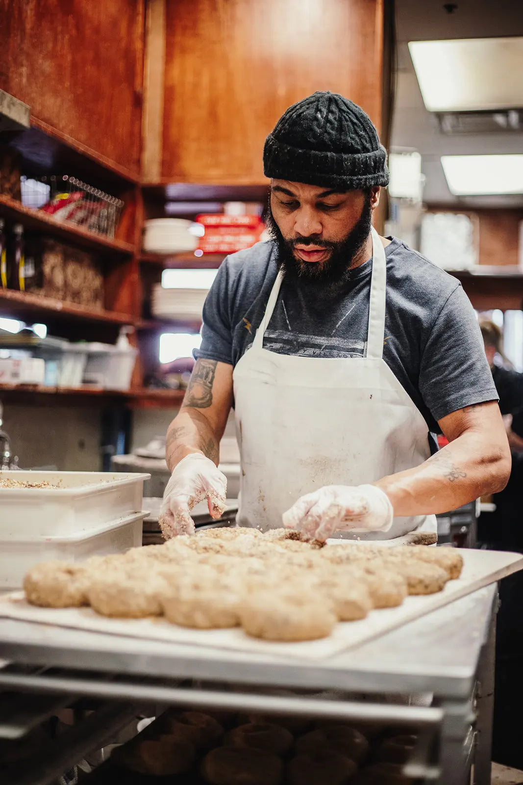 Person in a kitchen preparing food, wearing an apron and gloves.