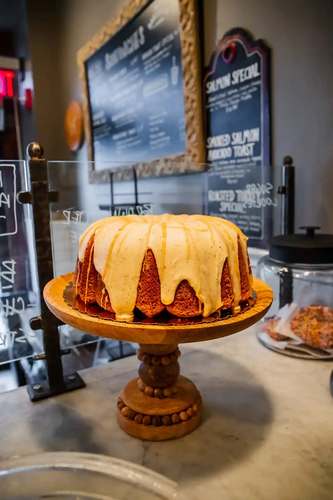 Bundt cake on a wooden stand with a menu in the background