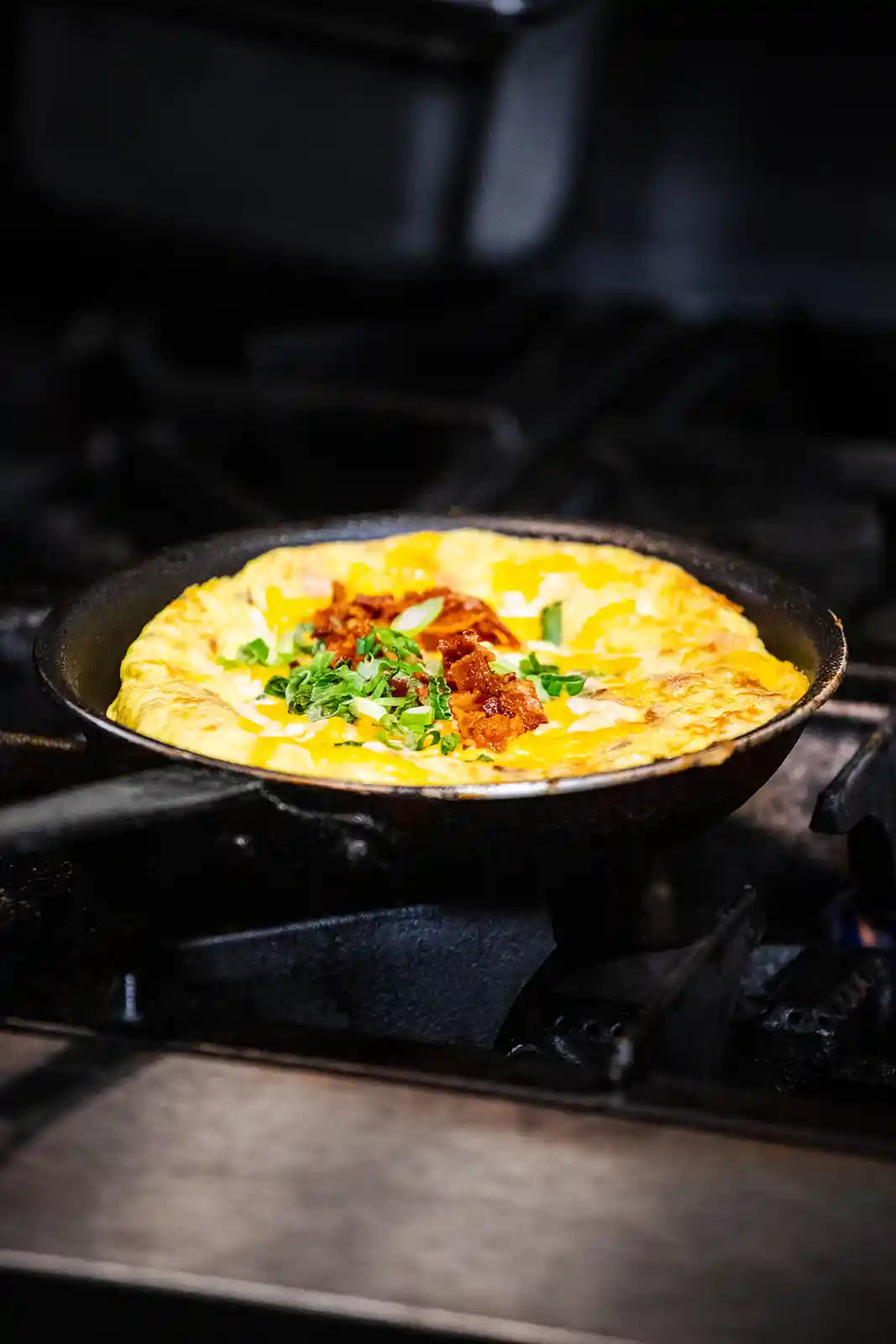 Omelette with toppings in a frying pan on a stove