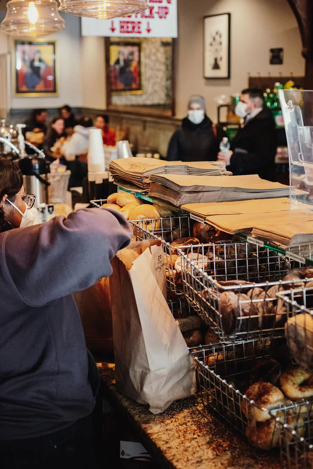 Bagel shop with customers and a display of bagels.