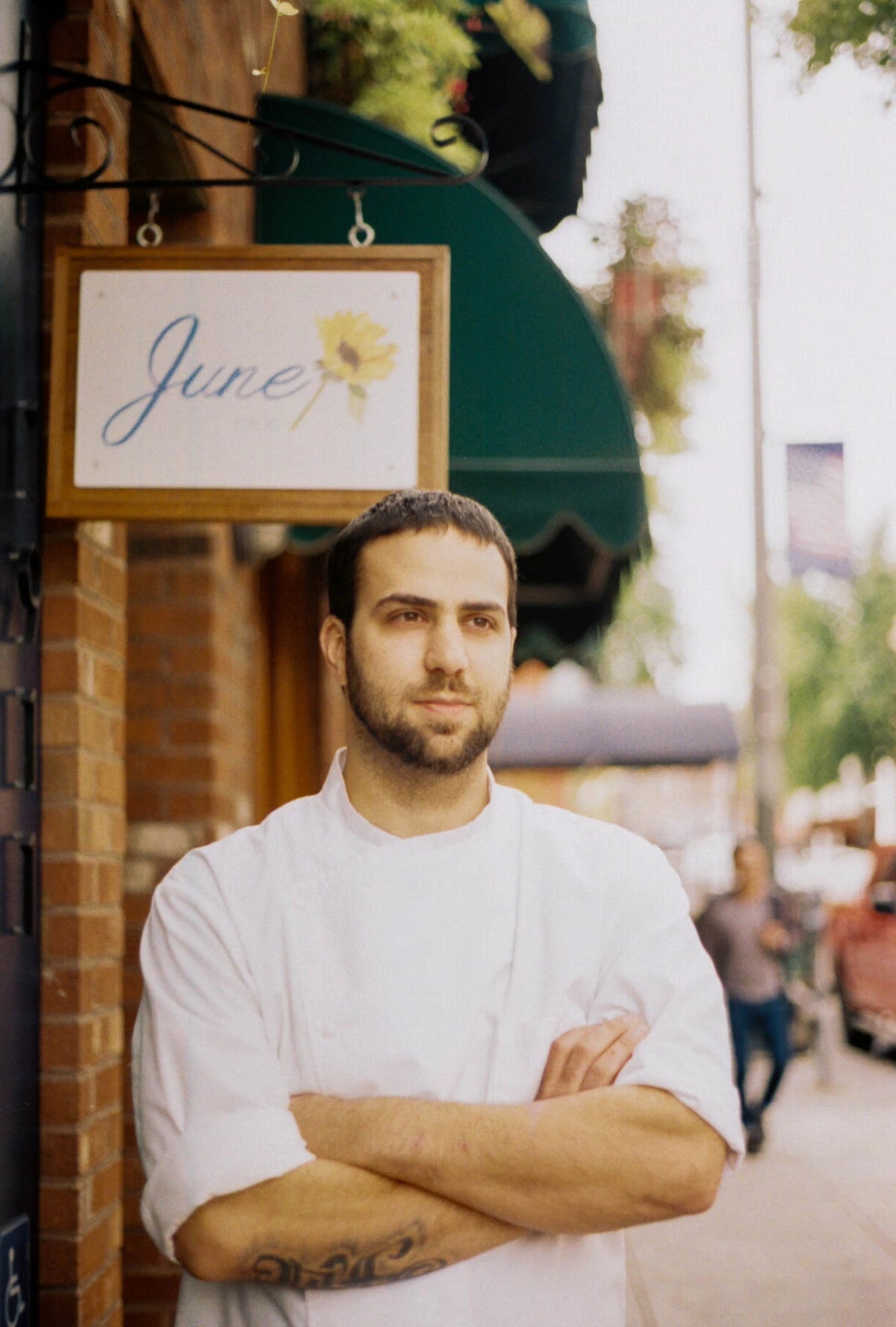 Man in a white shirt standing in front of a store with a 'June' sign. Chef Richard Cusack