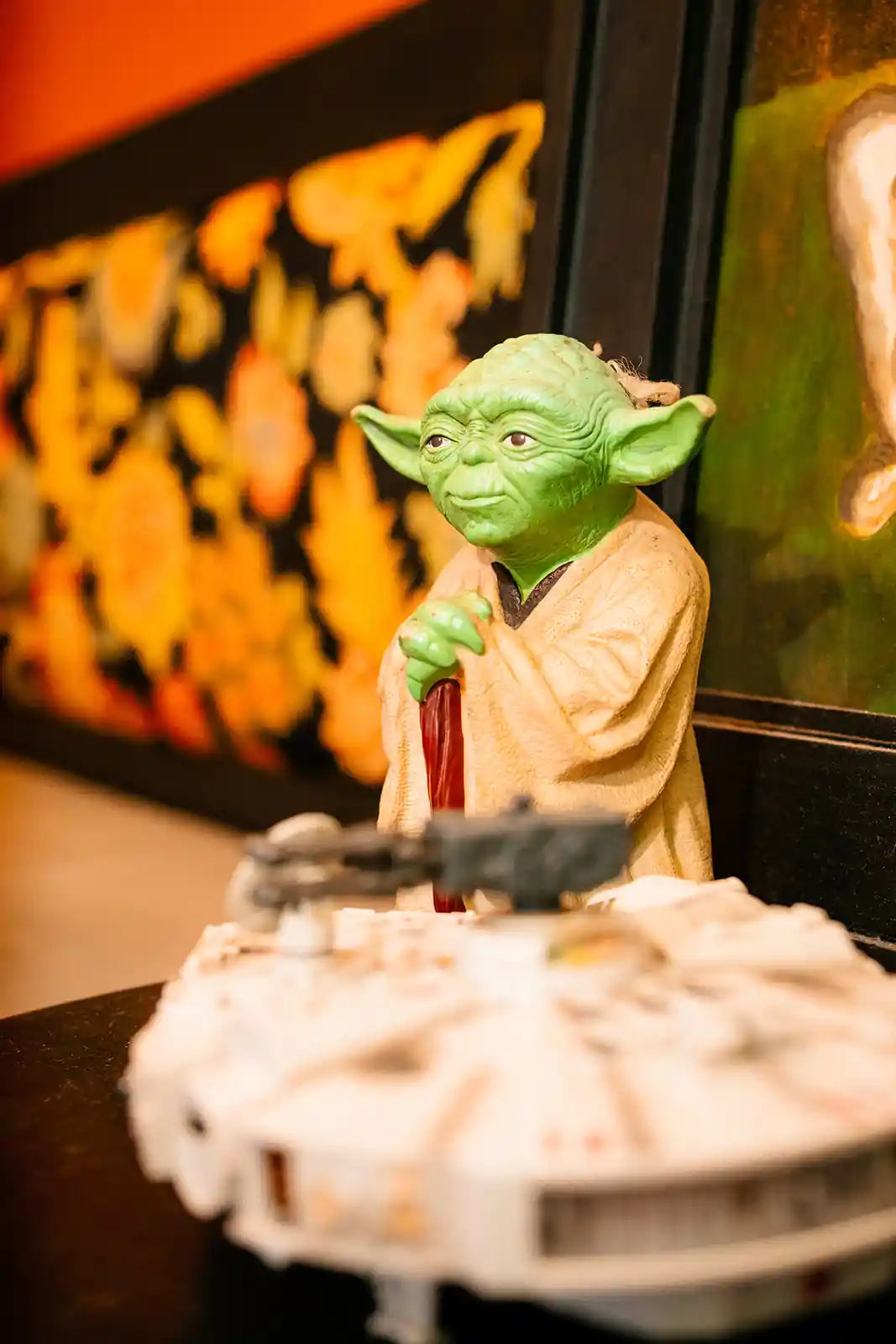 Yoda figurine on a cake with a colorful abstract painting in the background