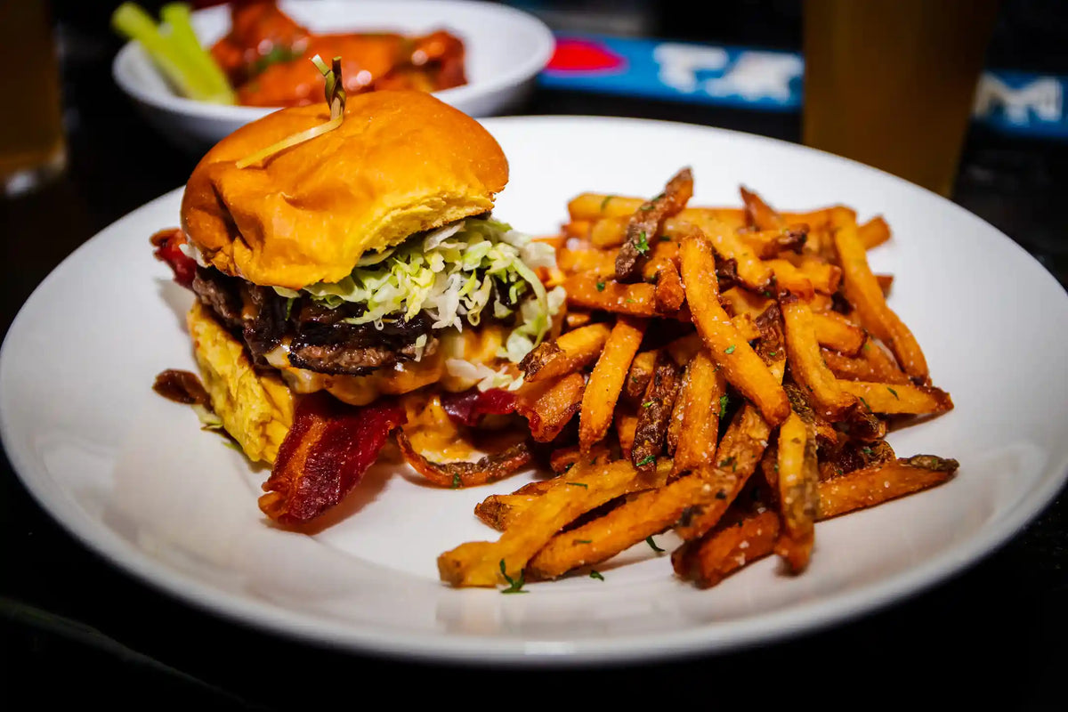 Burger and fries on a white plate with a blurred background