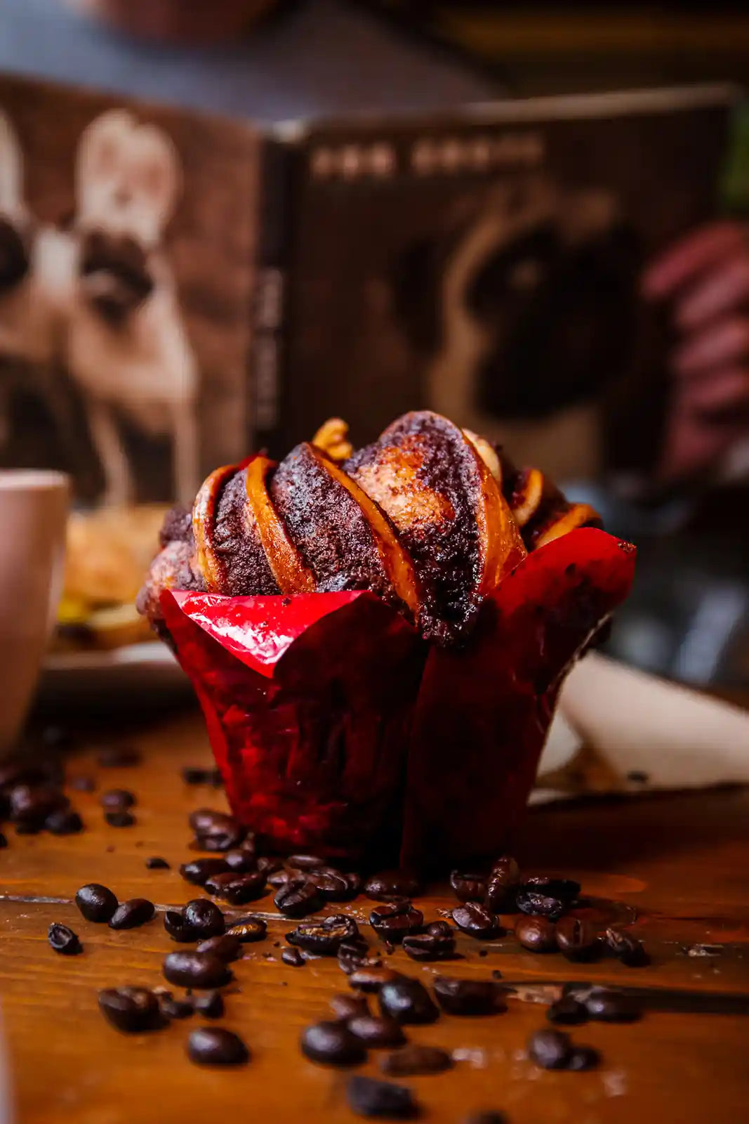 Cupcake with red wrapper on a wooden surface with coffee beans
