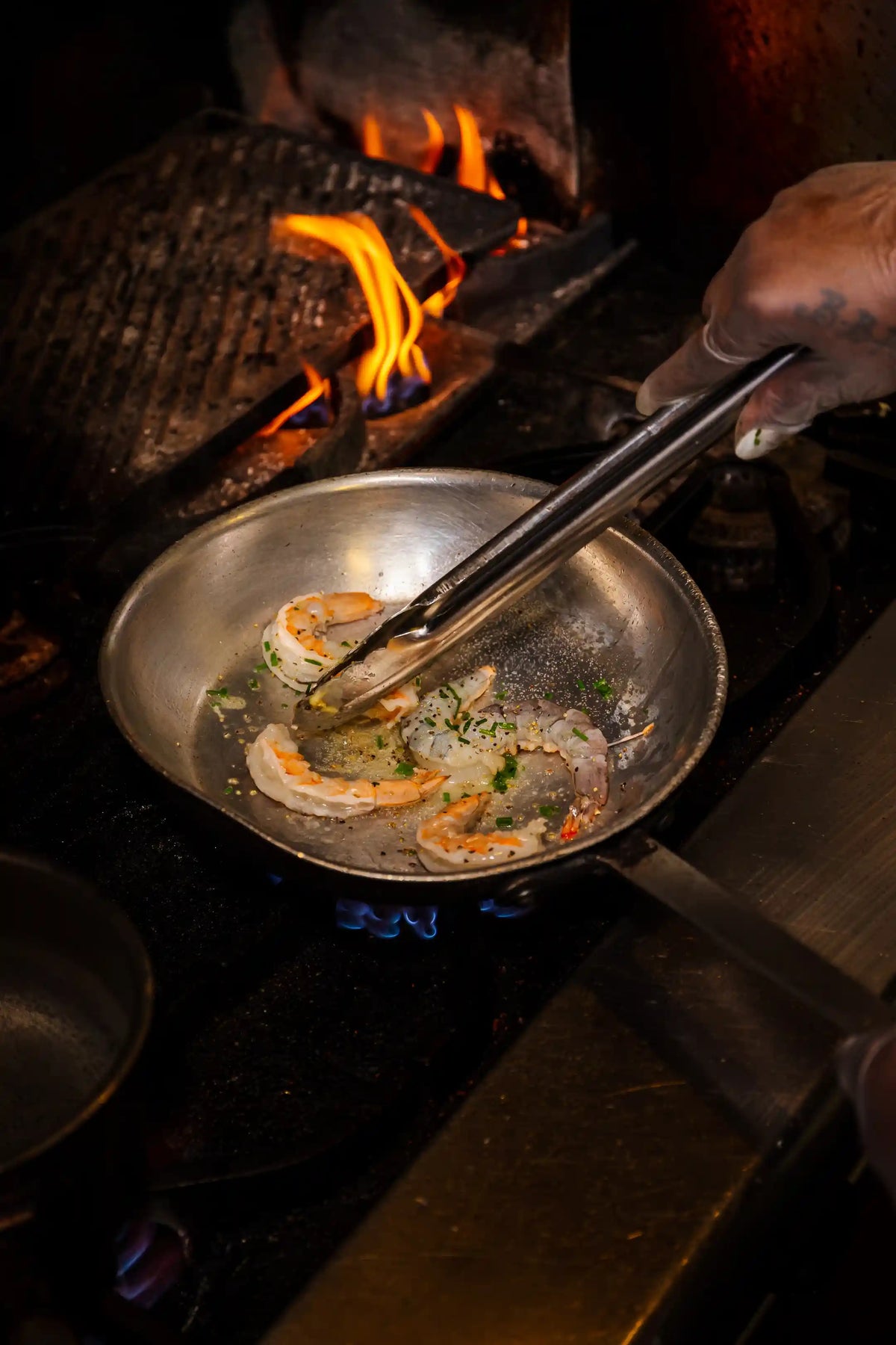 Person cooking food on a pan with flames in the background