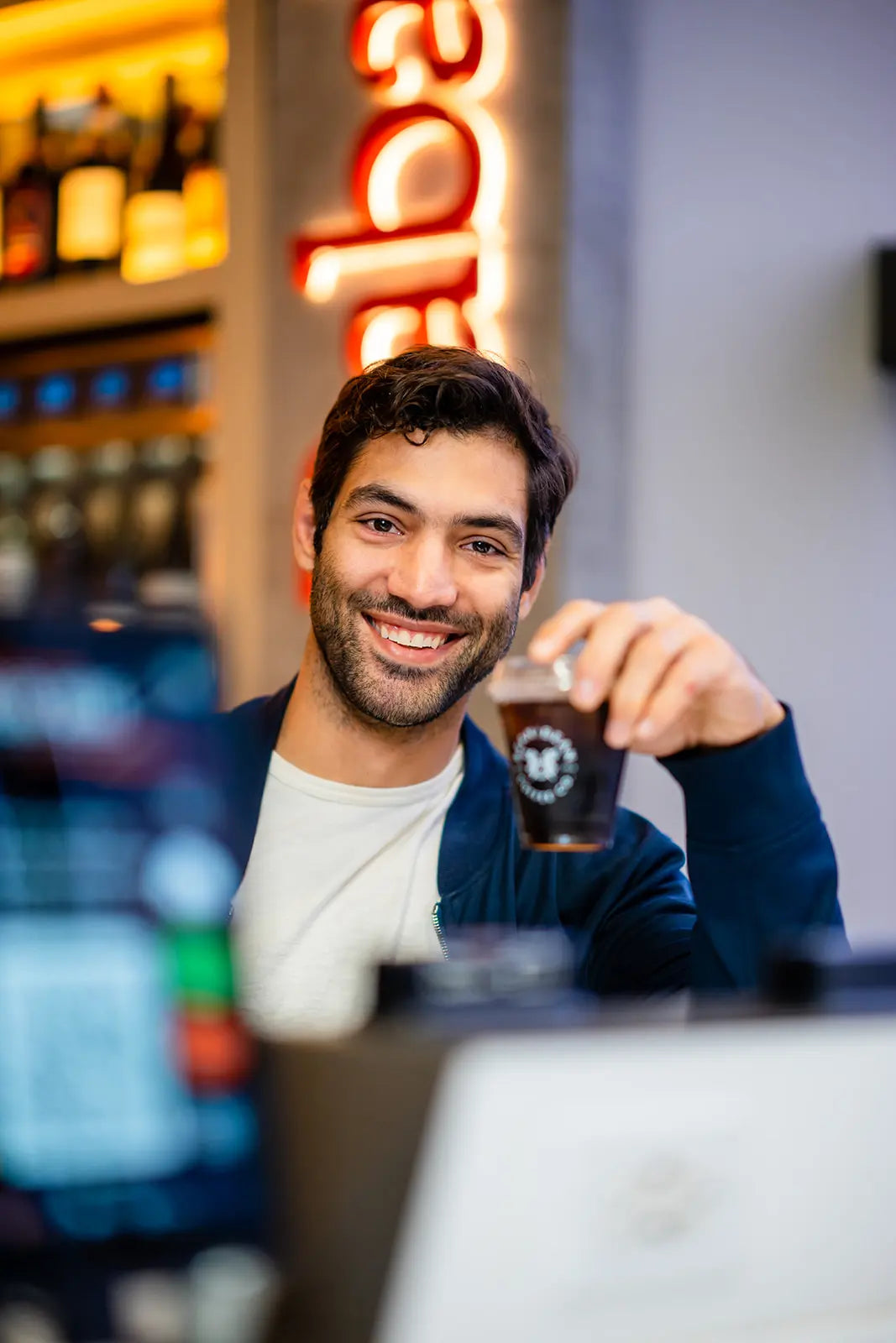 Man holding a Bean2Bean Cold Brew in Baba Bar with a blurred background