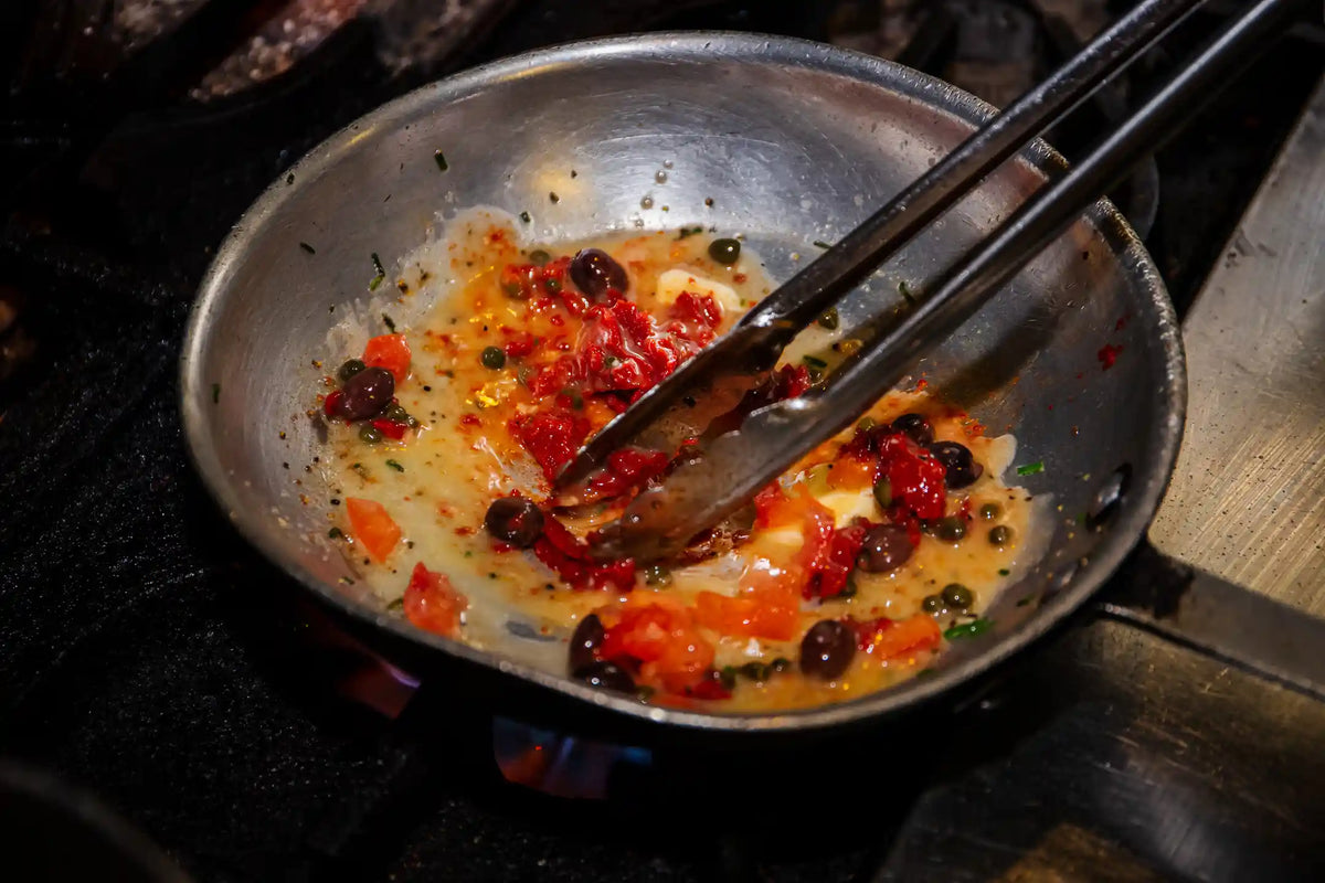 Frying pan with sautéed vegetables and spices on a stove