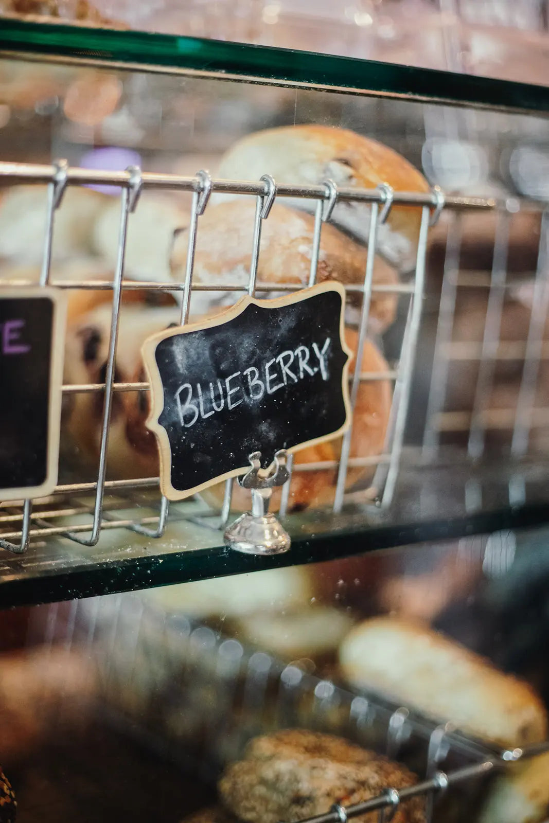Baked goods in a display case with a sign indicating 'Blueberry'.