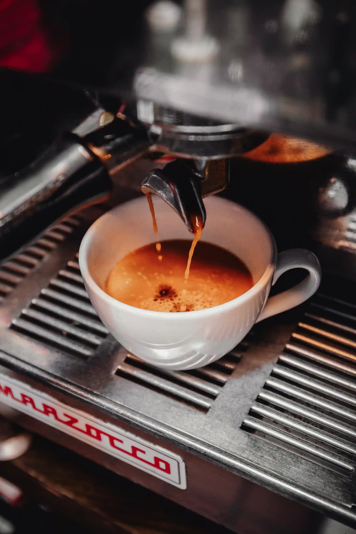 Bean2Bean Espresso being poured into a white cup from a Marzocco espresso machine.