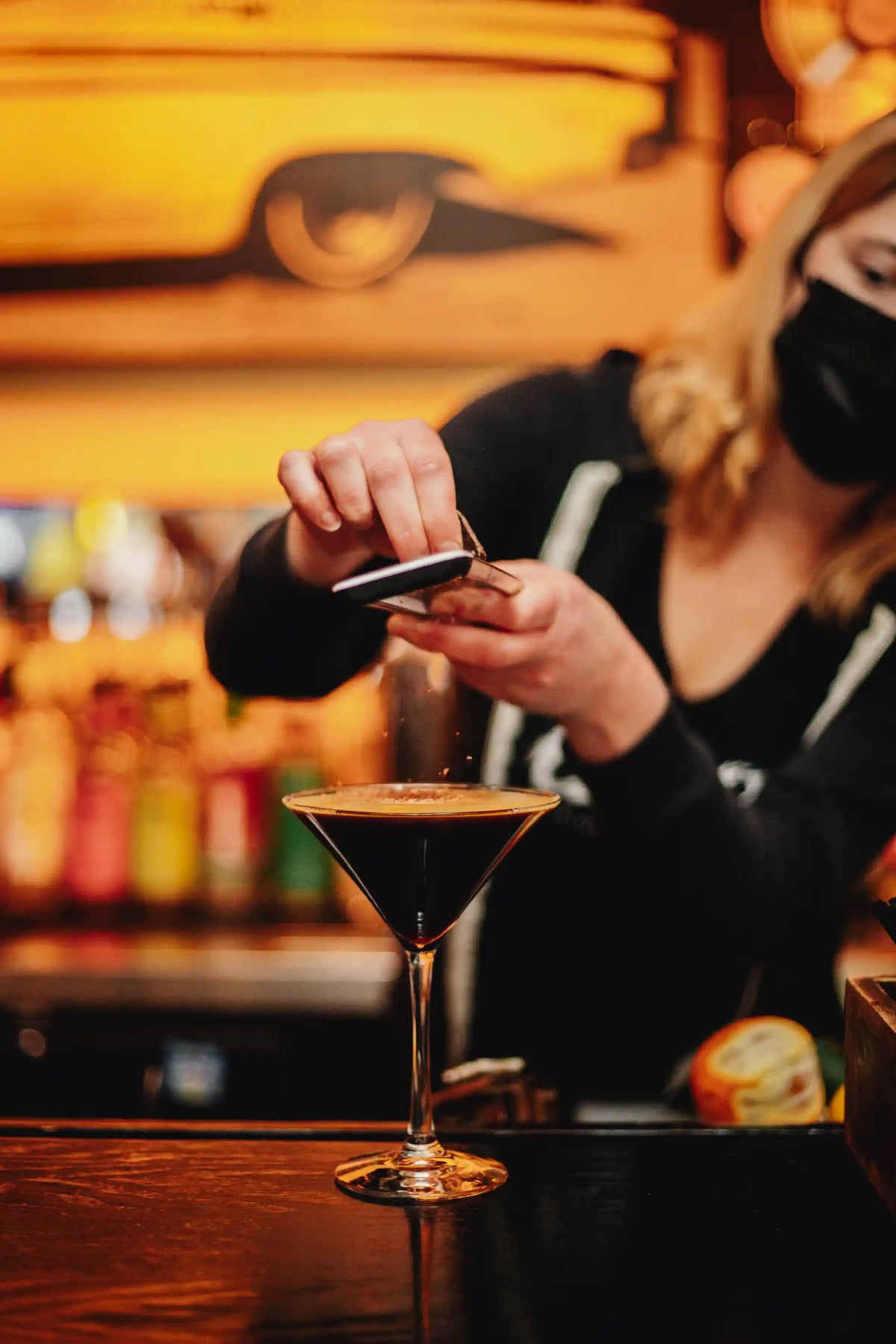 Bartender preparing a bean2bean espresso martini drink with a blurred bar background
