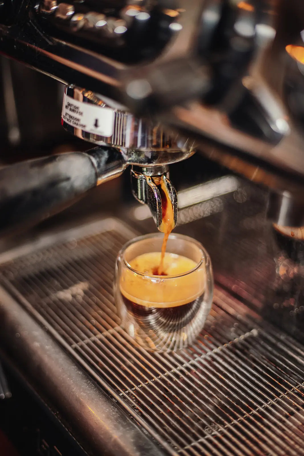 Espresso being poured into a glass from an espresso machine.
