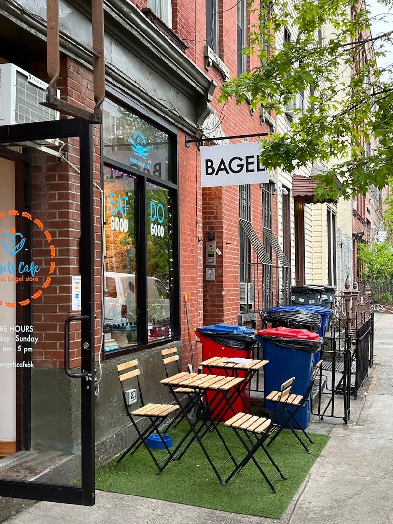 Outdoor seating area in front of a bagel shop with tables and chairs.